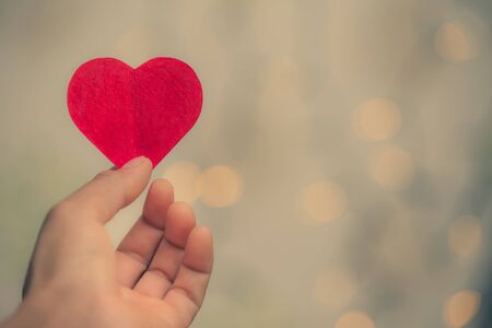Heart-shaped paper hand handle on bokeh background., Valentine's Day beautiful backgroundの写真素材