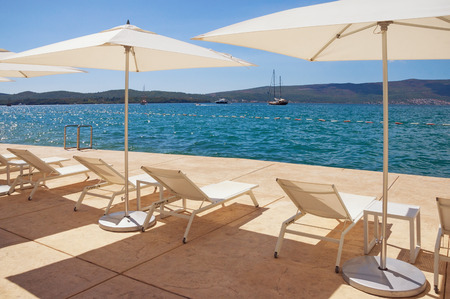 Sun umbrellas and chaise lounges on the beach on a sunny autumn day. Kotor  Bay of Adriatic Sea, Montenegroの写真素材