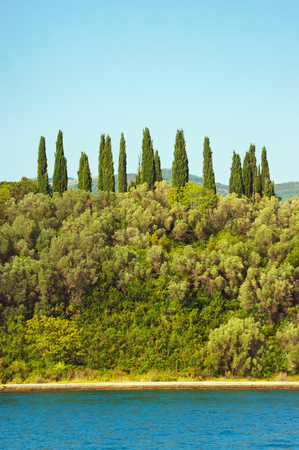 Mediterranean summer.  Horizontal stripes of sky, green trees and waterの写真素材