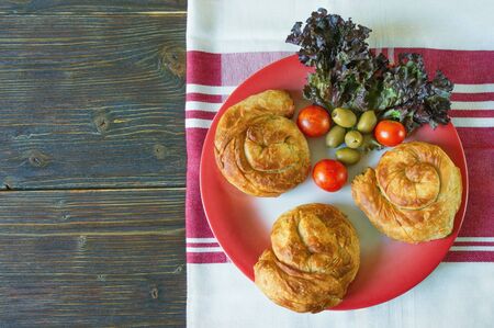 Balkan cuisine. Bureks - popular national dish - on red plate. Dark rustic background. Flat lay,...