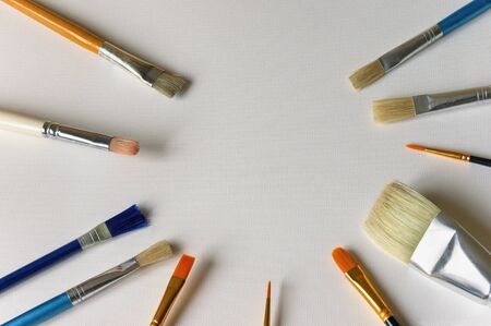 Different types of  paint brushes on sheet of white paper for painting. Free space for textの写真素材