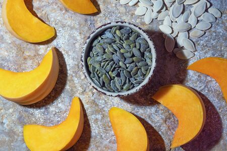 Pumpkin slices and seeds - in shell and peeled.  Natural stone backgroundの写真素材