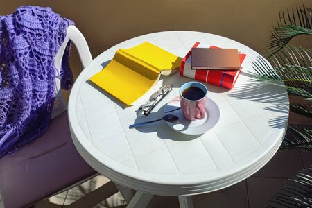  Cozy home still life: cup of coffee and opened book on balcony table; warm plaidの写真素材