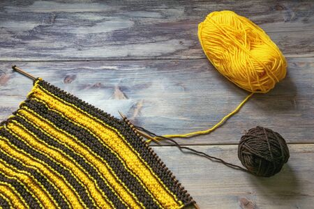 Hobby concept. Unfinished knitting, balls of wool and knitting  needles on rustic background. Free space for textの写真素材