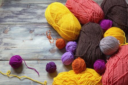 Hobby concept, knitting. Bright multi-colored skeins of wool on rustic table. Free space for text