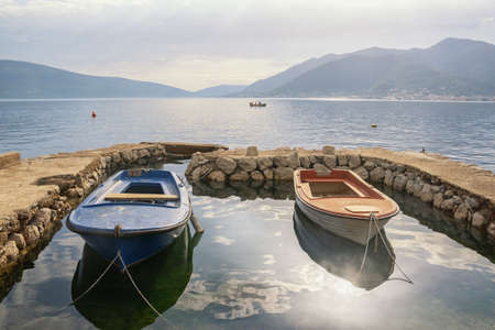 Beautiful Mediterranean landscape on foggy spring day. Fishing boats in small harbor. Montenegro, Adriatic Sea. View of Bay of Kotor near city of Tivatの写真素材