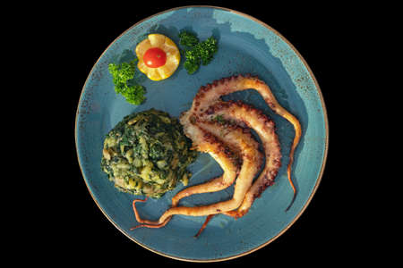 Balkan cuisine. Dish with grilled octopus with chard leaves ( blitva ) and potatoes, isolated on black background. Flat layの写真素材