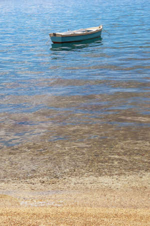 Minimalist landscape. Sand beach with color gradient from shore to deep water,  fishing boat on water.  Montenegro, Adriatic Seaの写真素材