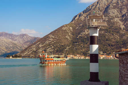 Beautiful Mediterranean landscape on sunny winter day. Montenegro, Adriatic Sea. View of beacon on coast of Kotor Bay and pleasure boat on water.  Island of St George and Perast town are in the distanceの写真素材