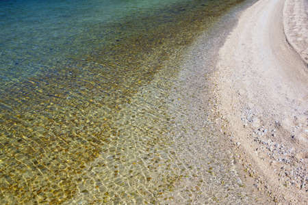 Sand beach of sea on calm sunny day, background. Radial color gradient from shore to deep water. Adriatic Sea, Montenegroの写真素材