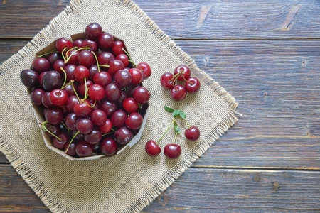 Fresh ripe cherries in cardboard box on rustic table. Flat lay. Free space for textの写真素材
