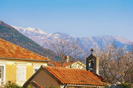 Spring in Mediterranean village. Cherry blossoms, red tiled roofs and small ancient church against snow-capped mountains. Montenegro, Tivat, Donja Lastva villageの写真素材