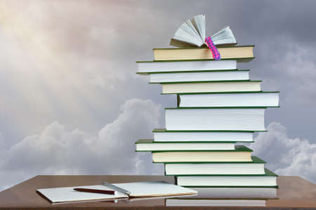 Autumn concept. Stack of books and exercise book on table against cloudy skyの写真素材