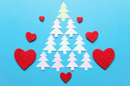 Paper fir-trees in the form of Christmas tree.  Red felt hearts. Blue background. Flat lay, copy spaceの写真素材