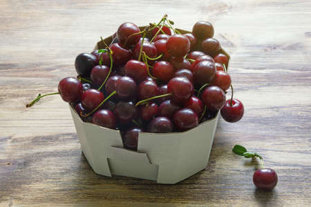 Cherries from market.  Fresh ripe fruits in cardboard box on rustic table.  Copy spaceの写真素材