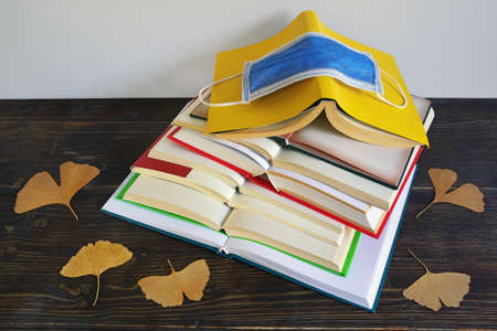 Autumn concept. Books, yellow leaves and face protective mask. Free space for textの写真素材