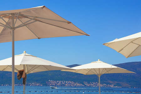 Summer vacation concept. White sun umbrellas against blue sky. Montenegro, Kotor Bay, Tivatの写真素材