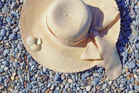 Vacations concept. Sun hat on pebble beach on sunny dayの写真素材