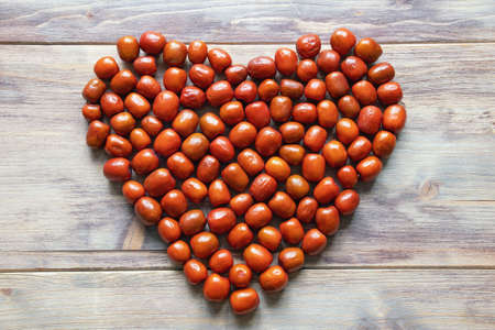 Fruit heart. Fresh red Jujube fruits ( Ziziphus jujuba ) on rustic table. Copy spaceの写真素材