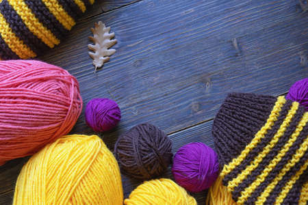 Hobby concept, knitting. Bright colorful skeins of wool on rustic table. Unfinished striped knitting. Free space for textの写真素材