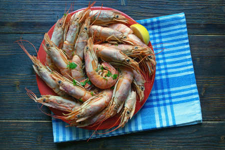 Boiled Adriatic shrimps in red plate on dark rustic tableの写真素材