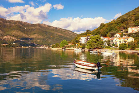 Sunny autumn day. Beautiful Mediterranean landscape, clouds and mountains are reflected in water. Montenegro, Adriatic Sea, Bay of Kotor, Tivat, view of Donja Lastva villageの写真素材