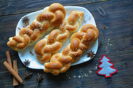 Homemade  sweet braided pastries with cinnamon,  sesame seeds  and star anise seeds on  dark rustic table. Copy spaceの写真素材