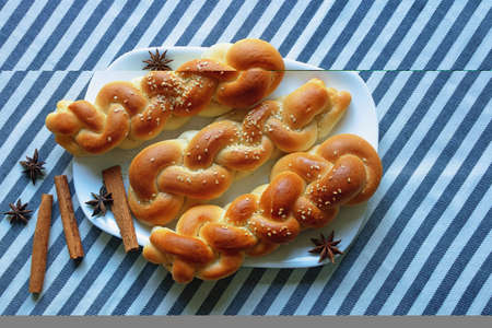 Homemade  braided pastries with cinnamon and sesame seeds on  table with striped tablecloth. Copy spaceの写真素材