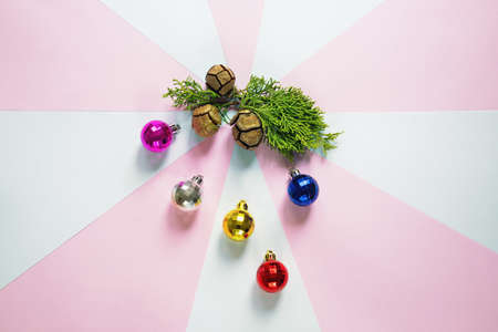 Colorful Christmas balls and green cypress tree branch with cones on paper background. Flat lay, free space for textの写真素材