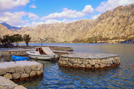 Beautiful Mediterranean landscape on sunny winter day. Montenegro,  Adriatic Sea. View of Kotor Bay near Prcanj town. Fishing boats in small harbor.  Dobrota town in distanceの写真素材
