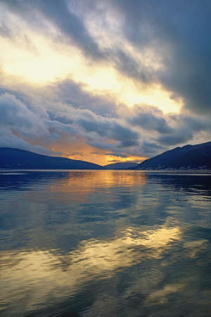 Beautiful autumn sunset.  Montenegro, Adriatic Sea, Bay of Kotor. Mountains and colorful clouds  are reflected in waterの写真素材