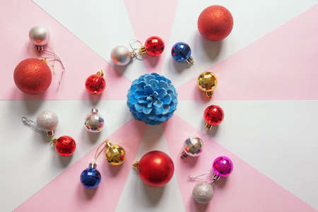 Bright Christmas balls and blue pine cone on multi-colored paper background. Flat lay, free space for textの写真素材