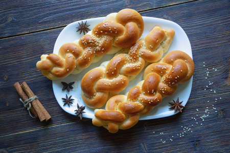 Homemade  braided pastries with cinnamon and sesame seeds on dark rustic tableの写真素材