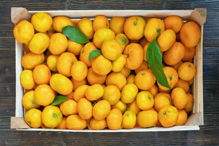 Fruit at the market. Fresh ripe tangerines in wooden box  on dark rustic tableの写真素材