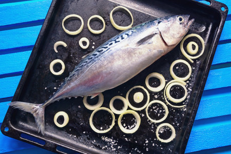 Fresh raw fish of tuna on black baking sheet. Flat lay. Blue rustic background