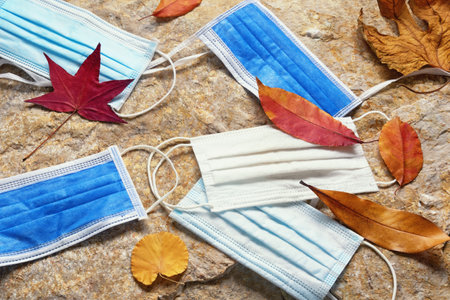 Discarded medical face masks among autumn leaves. Environmental pollution conceptの写真素材