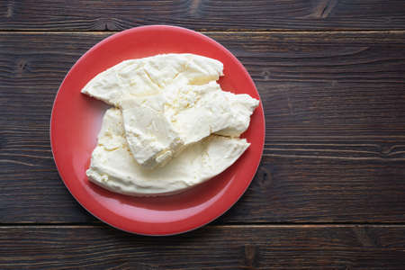 Balkan cuisine. Montenegro. Pljevaljski cheese  - local soft white cheese in red plate on dark rustic table. Copy spaceの写真素材