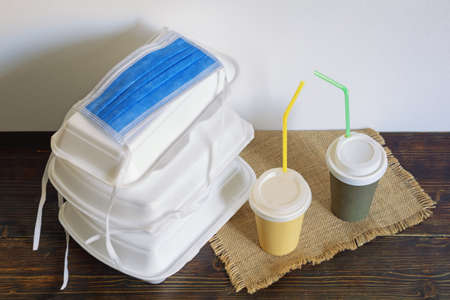 Food delivery. Takeout containers and face protective mask on rustic table. Copy spaceの写真素材