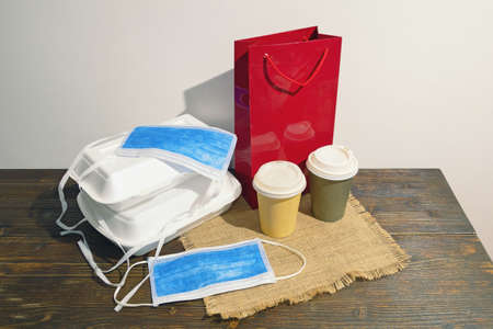 Food delivery. Various takeout containers and face protective mask on rustic table. Free space for textの写真素材