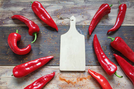 Red sweet peppers and cutting board on rustic table. Flat lay, copy spaceの写真素材