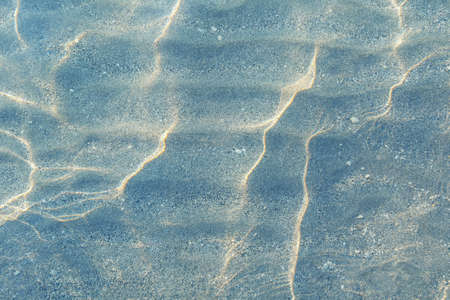 Shallow water,  sand beach on sunny day. Abstract texture, color tintingの写真素材