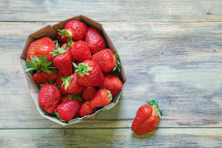 Strawberries from market. Fresh ripe fruit in cardboard box on rustic table. Flat lay. Free space for textの写真素材