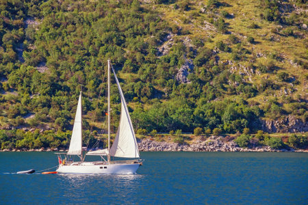 Sailboat sails  near shore of Bay of Kotor. Montenegro, Adriatic Sea. Travel conceptの写真素材