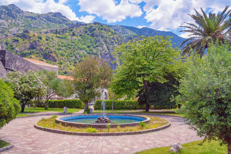Montenegro, Kotor city.  Square with fountain near  Old Town of Kotor and walls of ancient fortifications. Mountains and road to fortress in distanceの写真素材