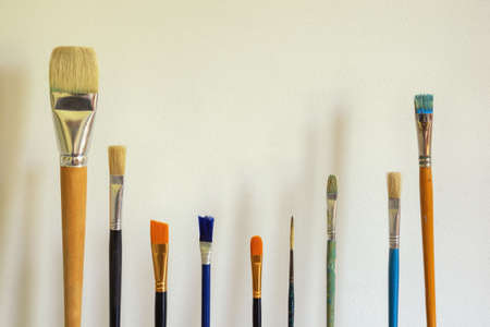 Different paint brushes against white rustic wall. Free space for textの写真素材