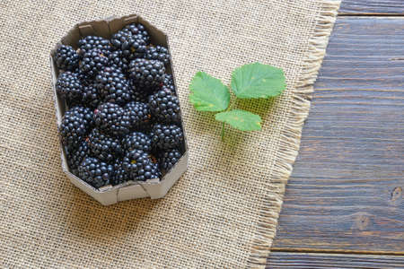 Blackberries from market.  Fresh ripe blackberries in cardboard box on rustic table. Flat lay. Free space for textの写真素材