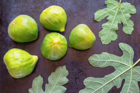 Ripe fig fruit and green leaves of a fig tree on black metal background.  Flat layの写真素材