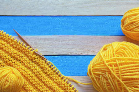 Hobbies and knitting concept.  Knitted cloth with knitting needles and skeins of wool on  rustic table. Space for textの写真素材