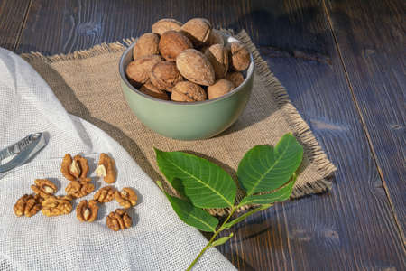 Whole walnuts and kernels on dark rustic table.  Leaves of walnut tree.  Copy spaceの写真素材