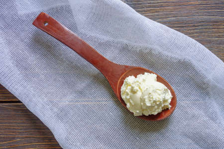 Balkan cuisine. Wooden spoon with kaymak - local soft white cheese.  Montenegro. Dark rustic table, copy spaceの写真素材